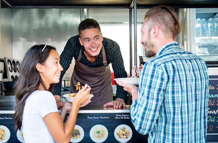 Image of a man and woman ordering from a man in a food truck