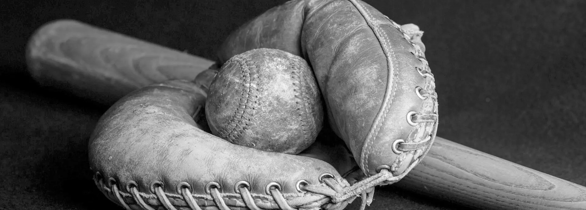 Image of an old baseball in an old glove and bat
