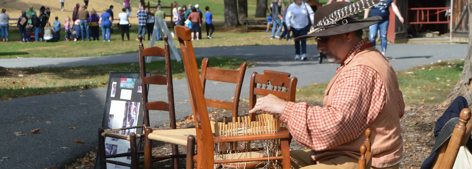 Image of a man wearing a hat with a turkey feather re-caining a chair