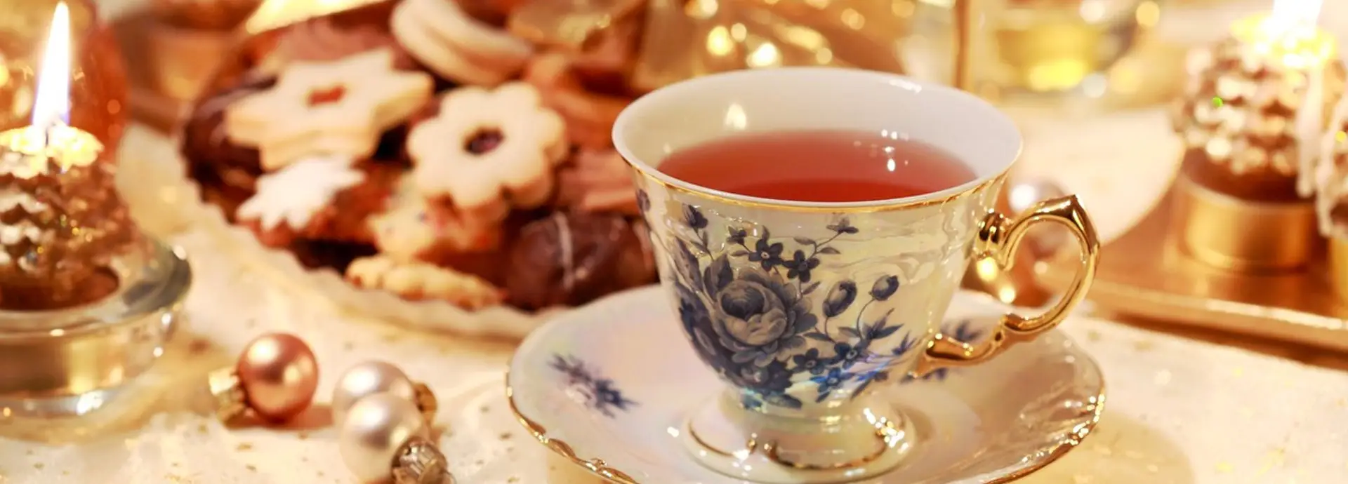 Image of a tea cup with cookies and scones in the background.